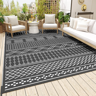 A black and white printed rug in a garden on a patio. 