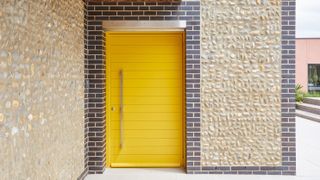 modern yellow front door with brick details around