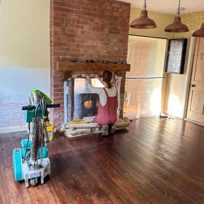 a woman partway through a diy project of sanding her wooden floor