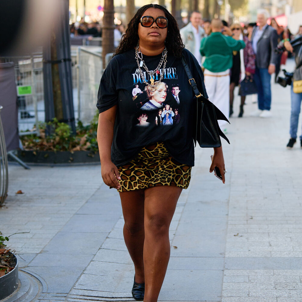 Gabriella walks with conviciton down a bumbpy street wearing a leopard print skirt and black top. 