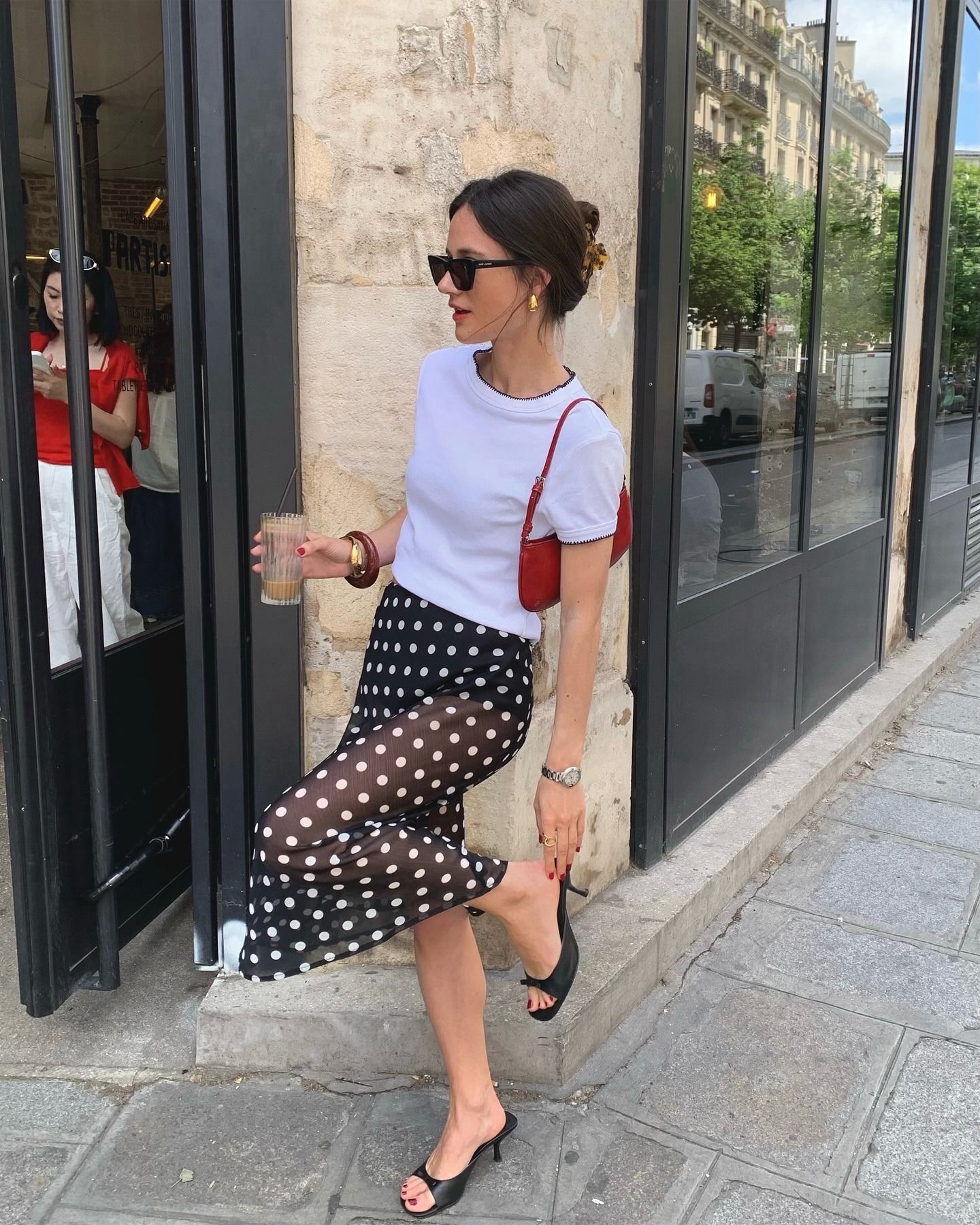 Woman in white t-shirt, polka-dot skirt, and black sandals