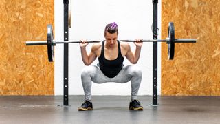 Woman performing barbell squat in a gym