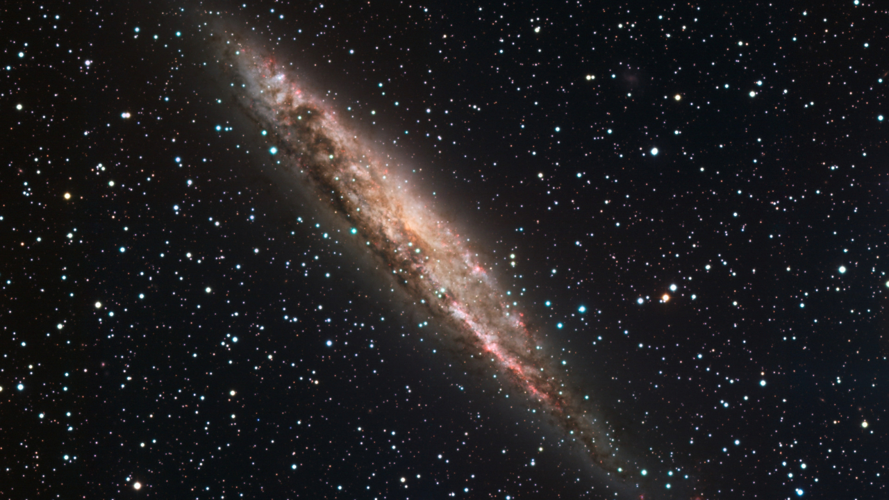 A spiral galaxy is tilted at a 45 degree angle amidst stars in space.