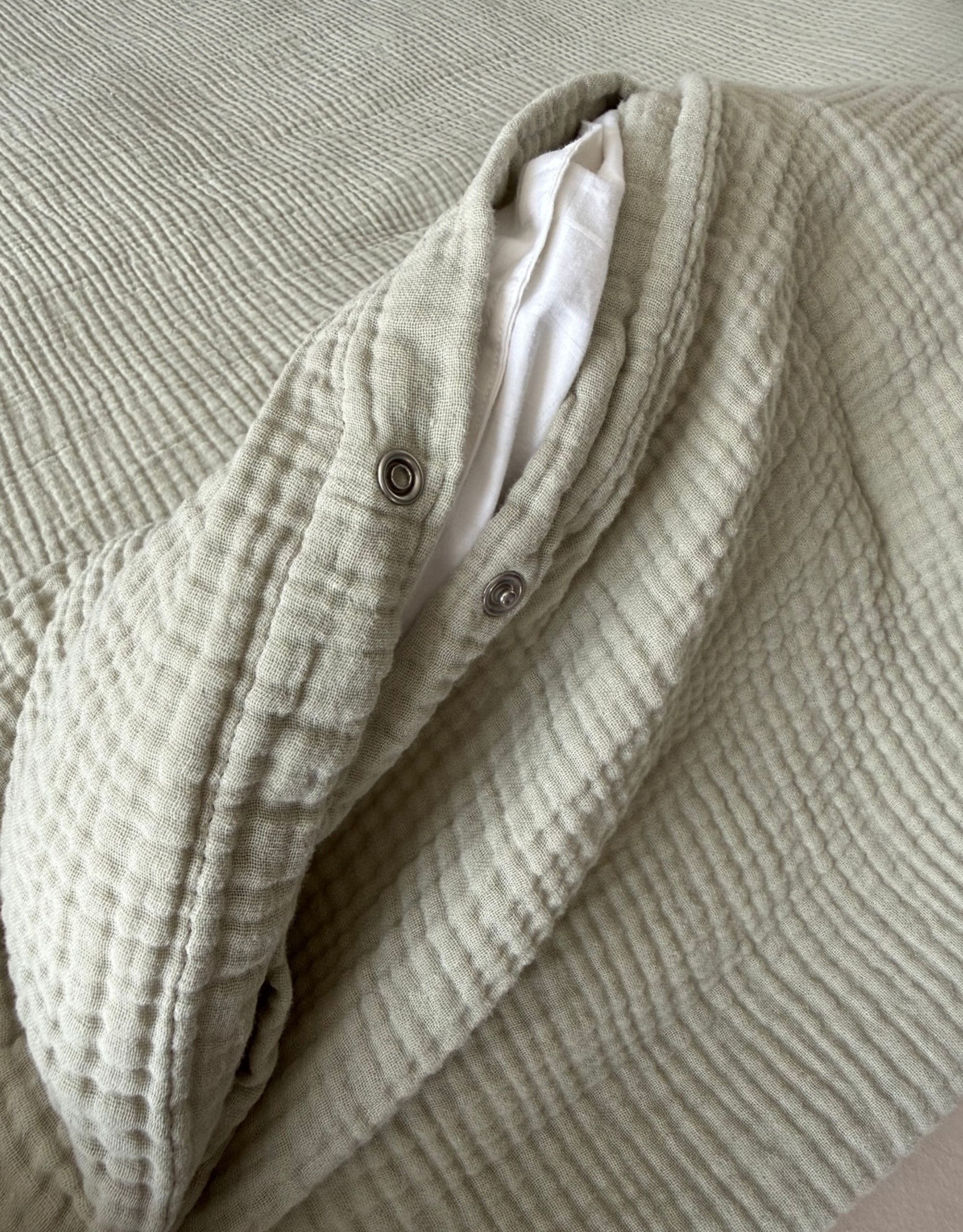 A close up of the metal-press studs used to open and seal a light green duvet cover