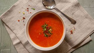 Tomato soup in bowl with metal spoon