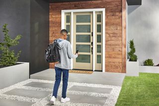 A boy walking up a path to a home with a smart door