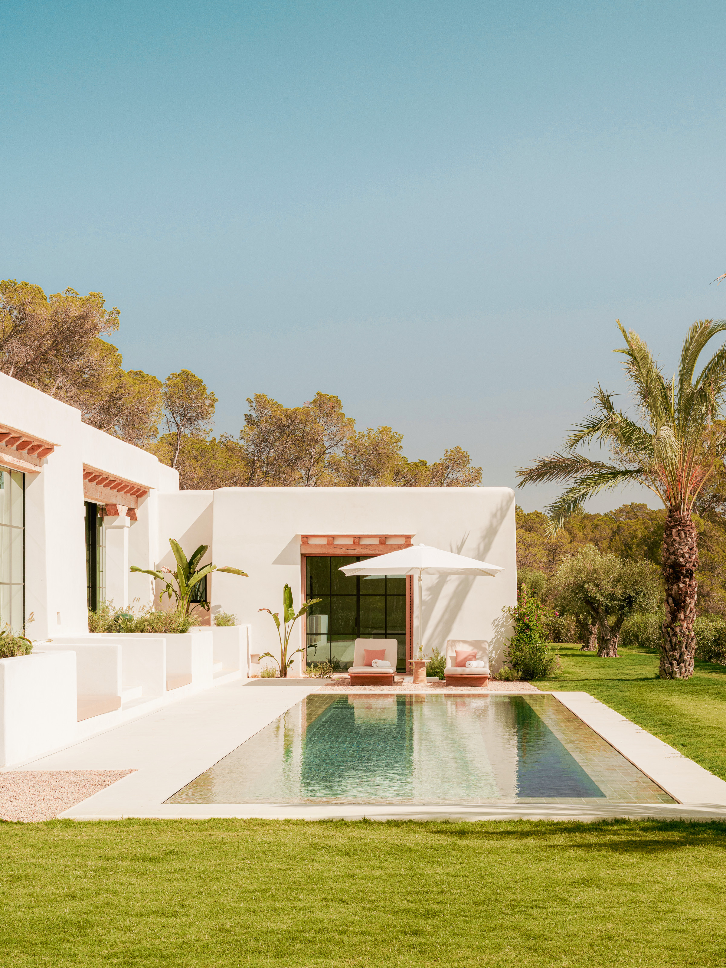 View of white villa from outside with pool, parasol and sunloungers