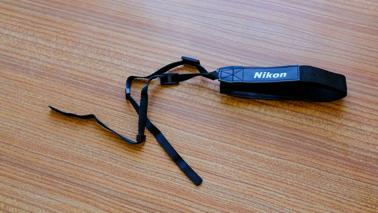 The neckstrap for the Nikon Action 7x50 binoculars on a wooden table.