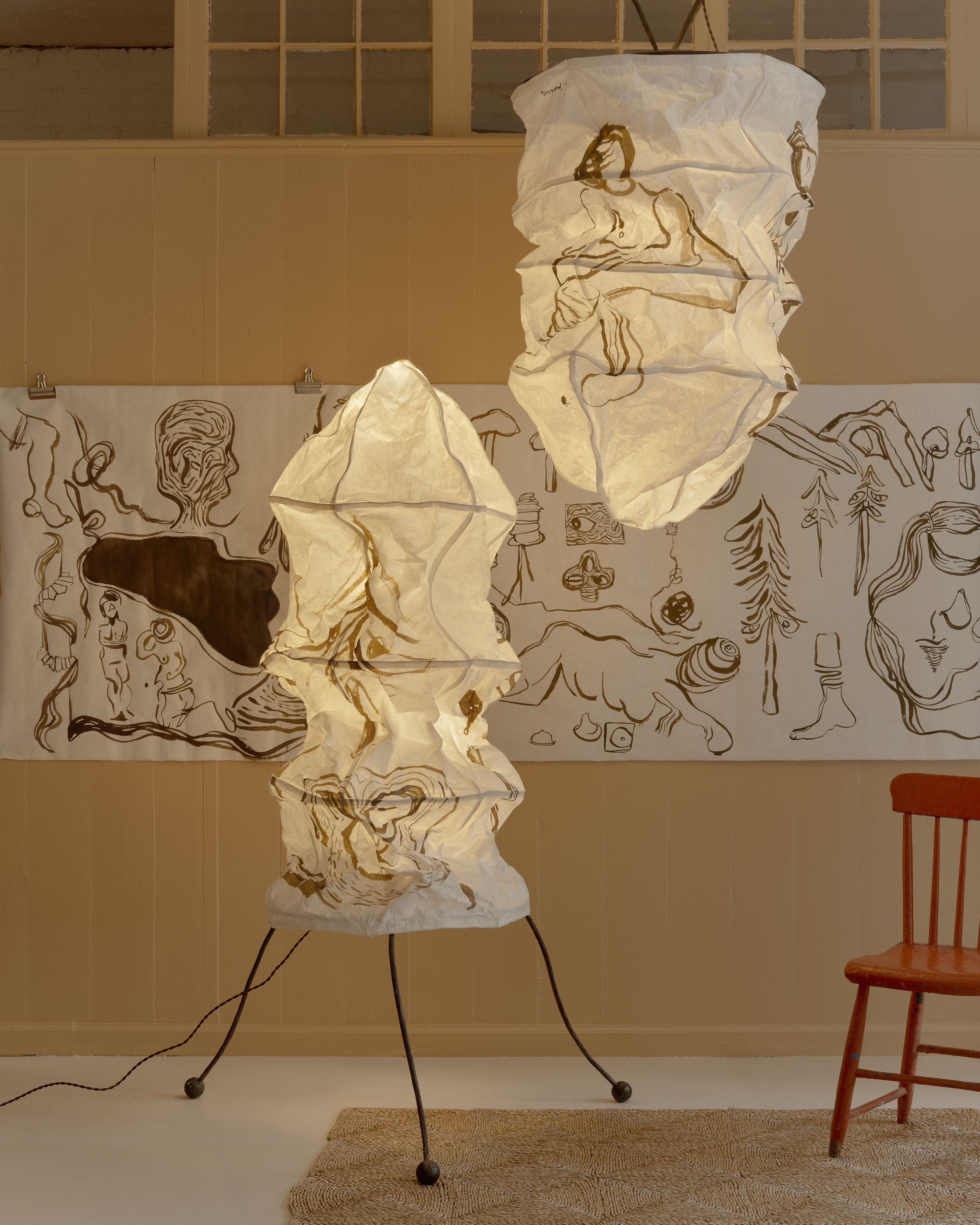 paper lamps on a rush mat against a beige wall hung with artwork