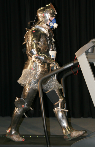 A volunteer in full knight armor walks on a treadmill.