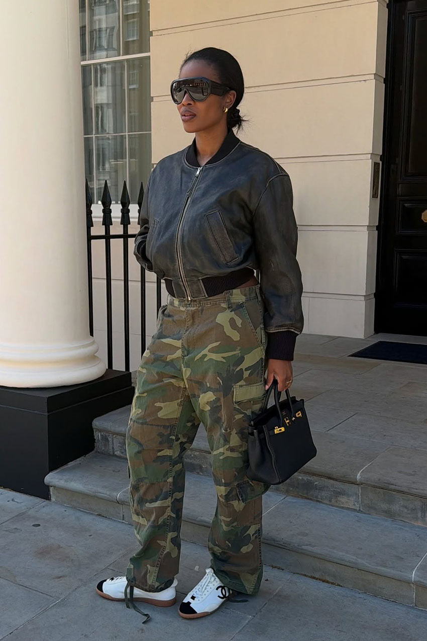 A woman wearing leather bomber jacket and camo pants.