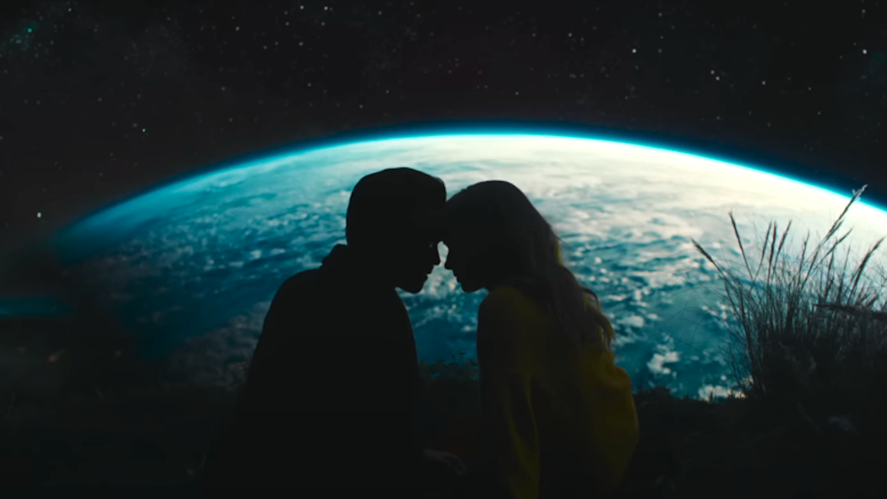Colin Farrell and Margot Robbie&#039;s silhouettes touching foreheads with the Earth behind them in A Big Bold Beautiful Journey still