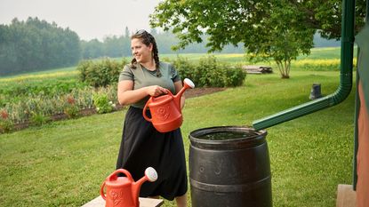 woman using rainbarrel to fill watering cans for garden 