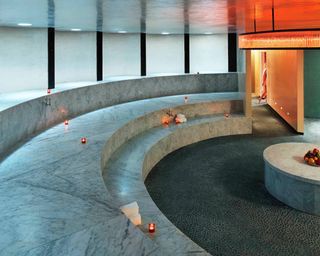 The futuristic interiors of a spa feature marble accents and suffused orange light.