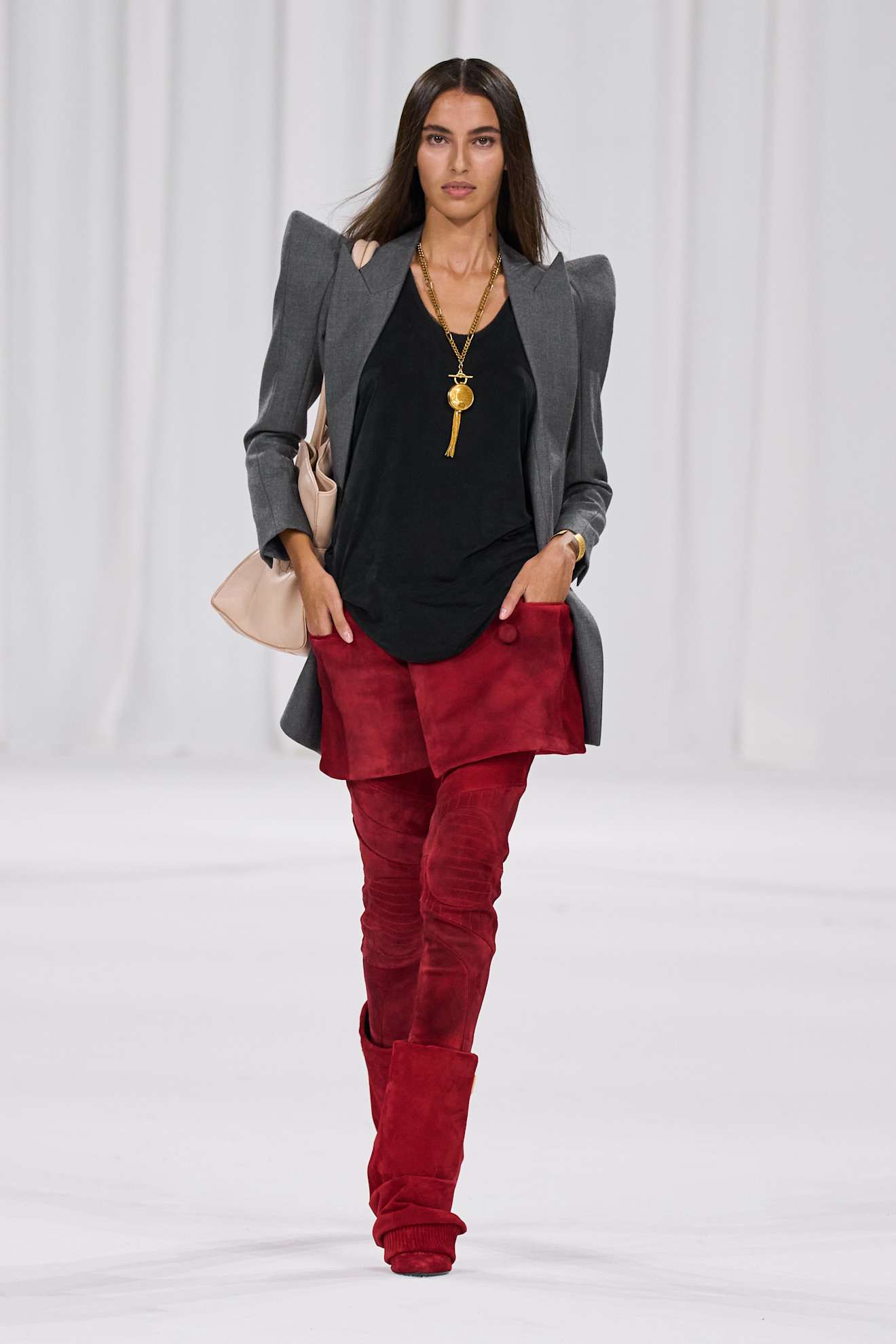 A woman is wearing a tassel-accented necklace on the Balmain S/S 25 runway.