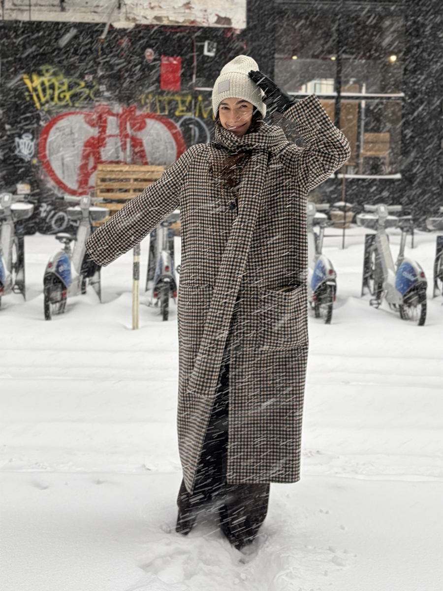 Melanie Masarin Ghia Founder in Snowy Weather Wearing Winter Outfit of Beanie and Checked Coat with Matching Scarf