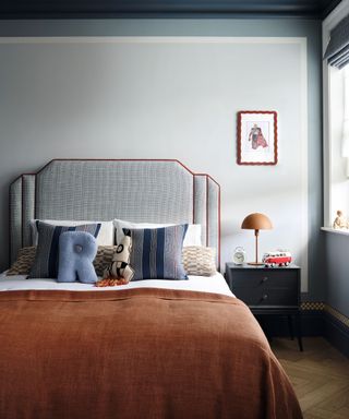 bedroom with orange bedspread and light grey walls