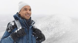 A man hiking in the snow wears insulated gloves