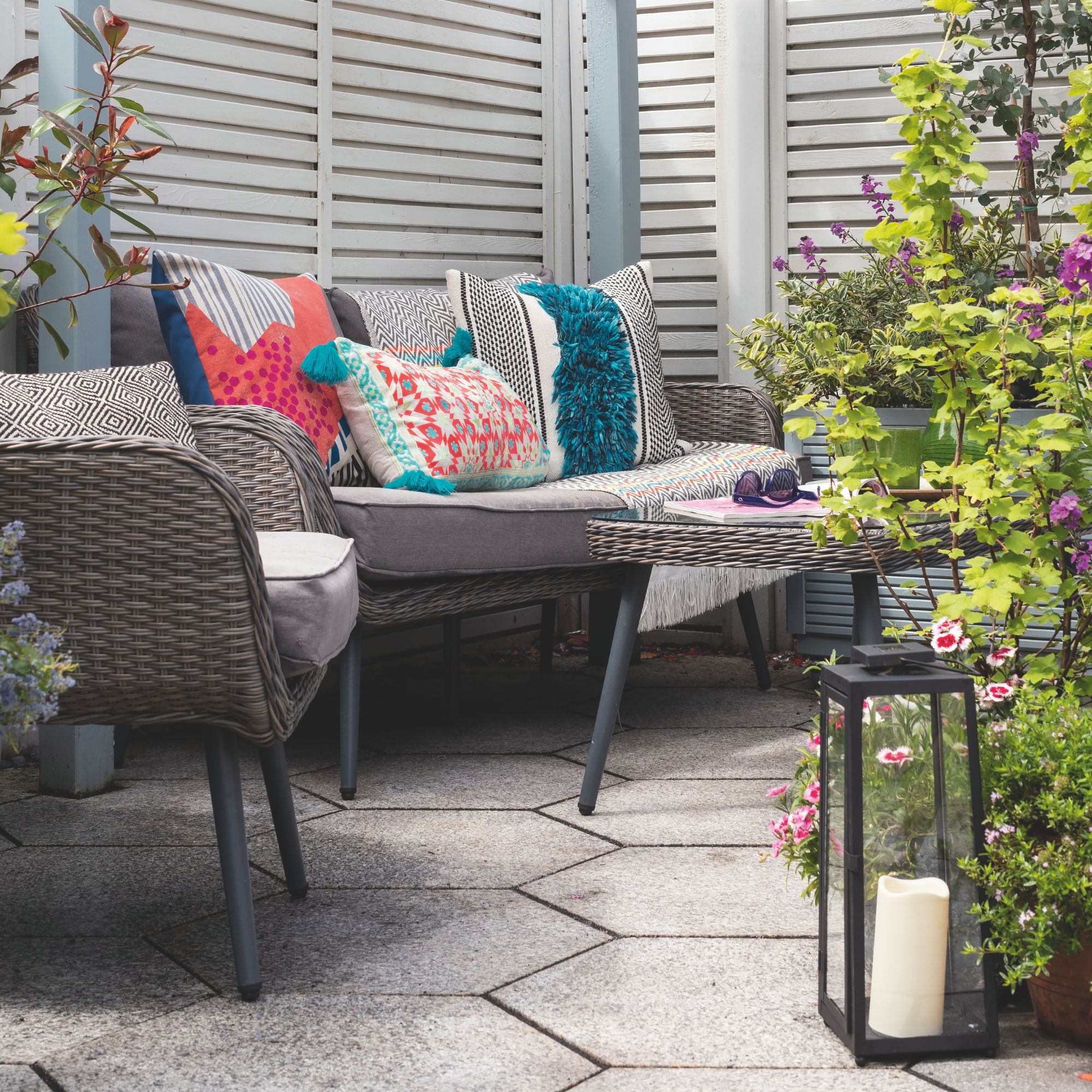 Outdoor seating area with cushions beneath wooden pergola with lantern