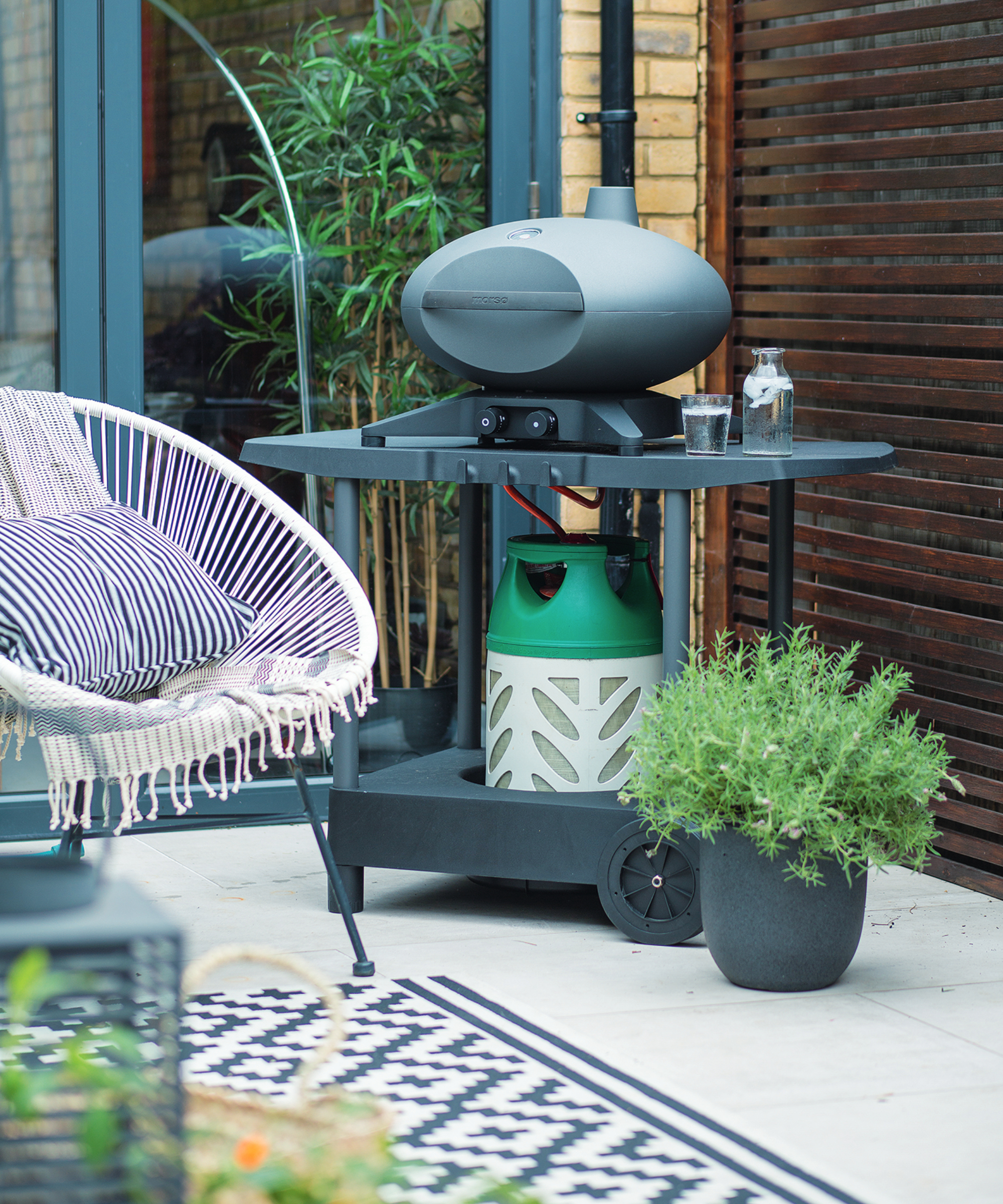 Barbecue on a modern patio with a pot of herbs