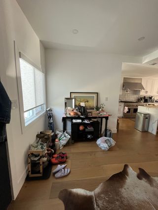 A crowded entrance area with a black console table and shoe rack