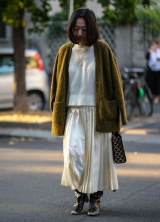 Woman wearing a cream skirt, jumper and oversized green cardigan