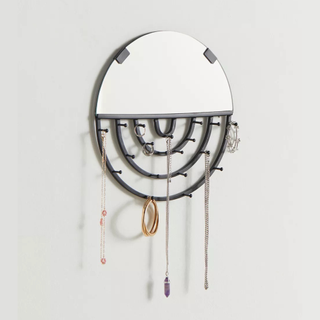A half-circle mirror with black wire arches to hang jewelry
