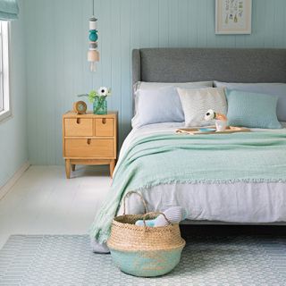 Pale blue bedroom with grey upholstered bed and bedding in soft pastel shades