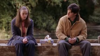 Alexis Bledel as Rory Gilmore and Milo Ventimiglia as Jess sitting on a dock Gilmore Girls