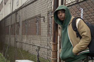 Thaddeus J Mixson as Demetrius, leaning against a city fence, in Episode 108 of The Madness.