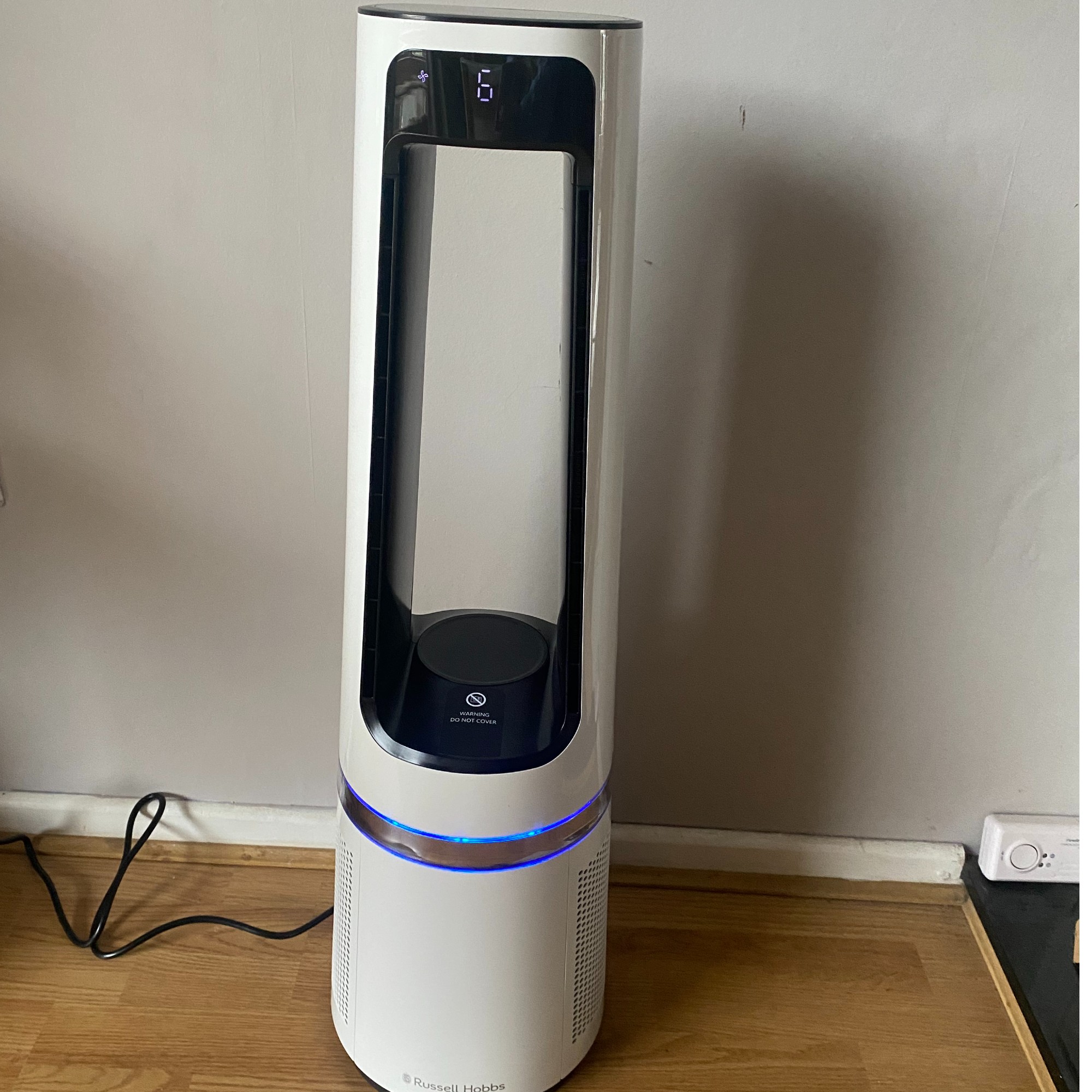 Russell Hobbs RHBLDL25 Bladeless Fan Heater in cooling mode on a wood effect floor and in front of a taupe coloured wall