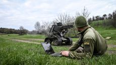 A Ukrainian soldier tests a robot with a machine gun attachment during a training session.
