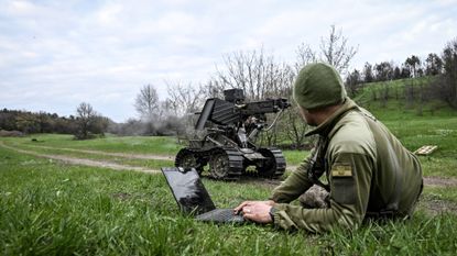 A Ukrainian soldier tests a robot with a machine gun attachment during a training session.