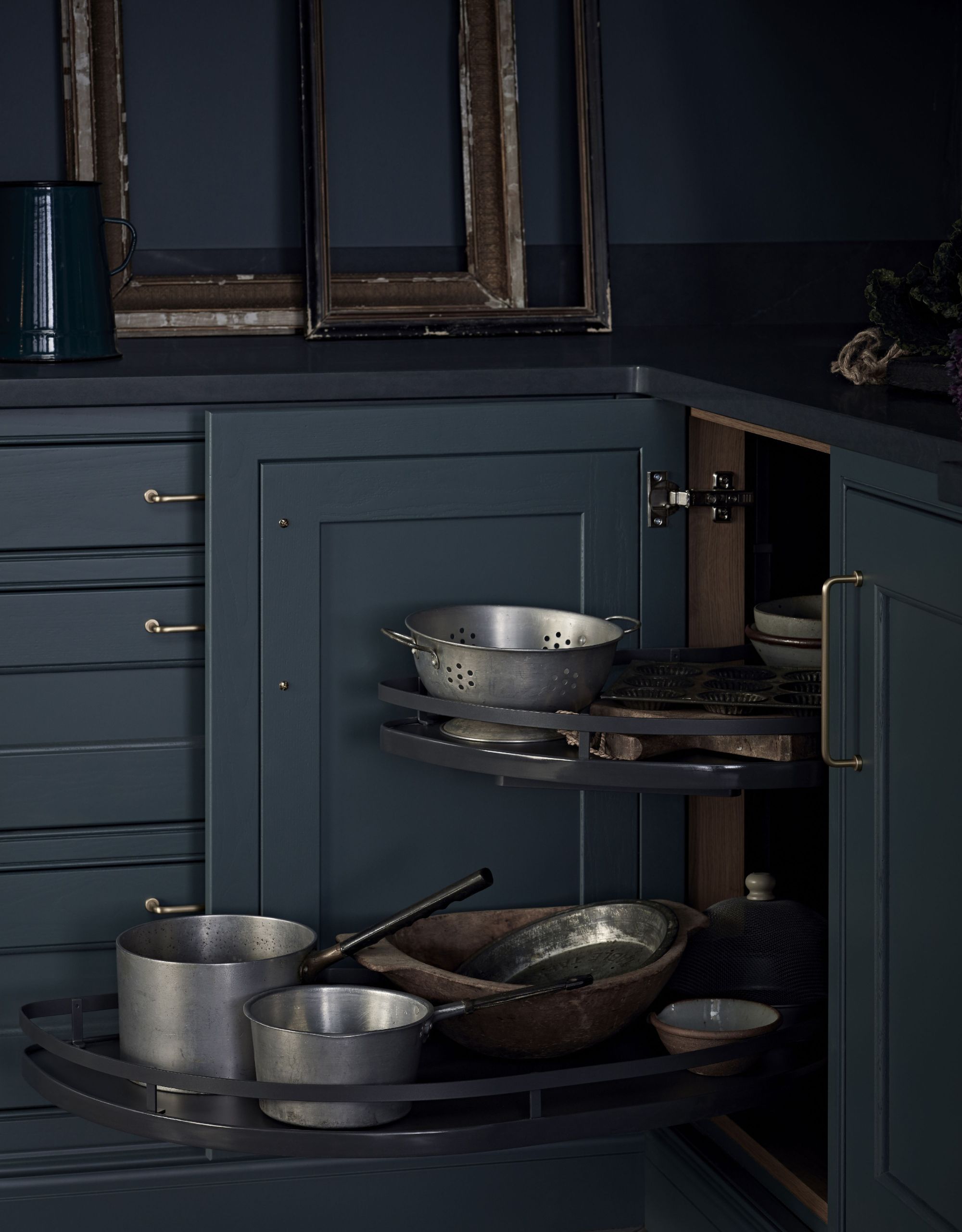 A navy blue kitchen corner with a cabinet door open to reveal pull-out drawers to store pots and pans