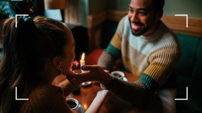 Couple sitting together over candlelit dinner, holding hands, showing the mood lighting needed to have sex