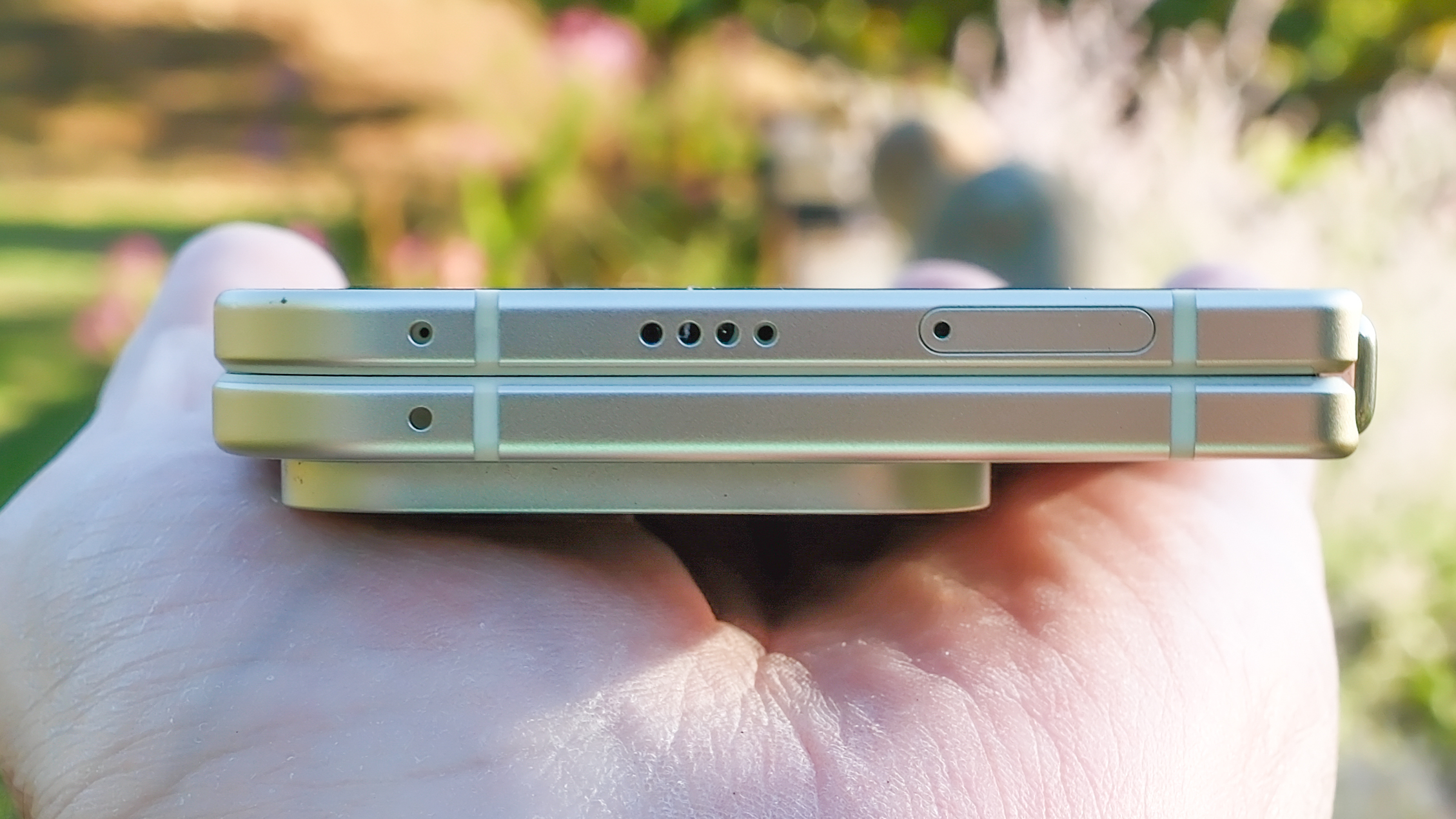 Google Pixel 10 Pro Fold in Jade green outside at a flower garden on a sunny day