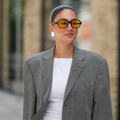 street style shot of woman with slicked bun and glowy makeup