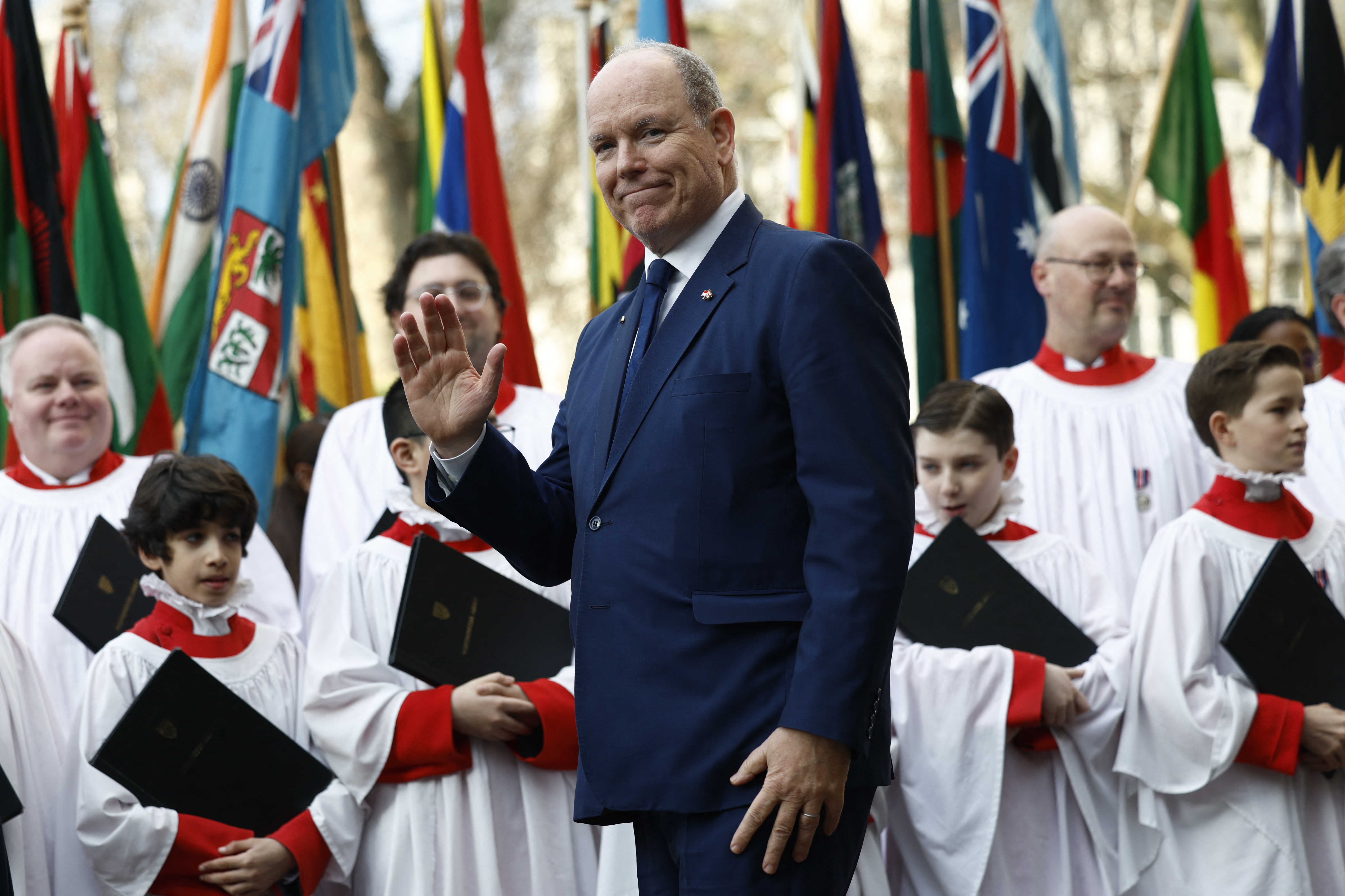 Prince Albert wearing a blue suit and waving in front of choir boys