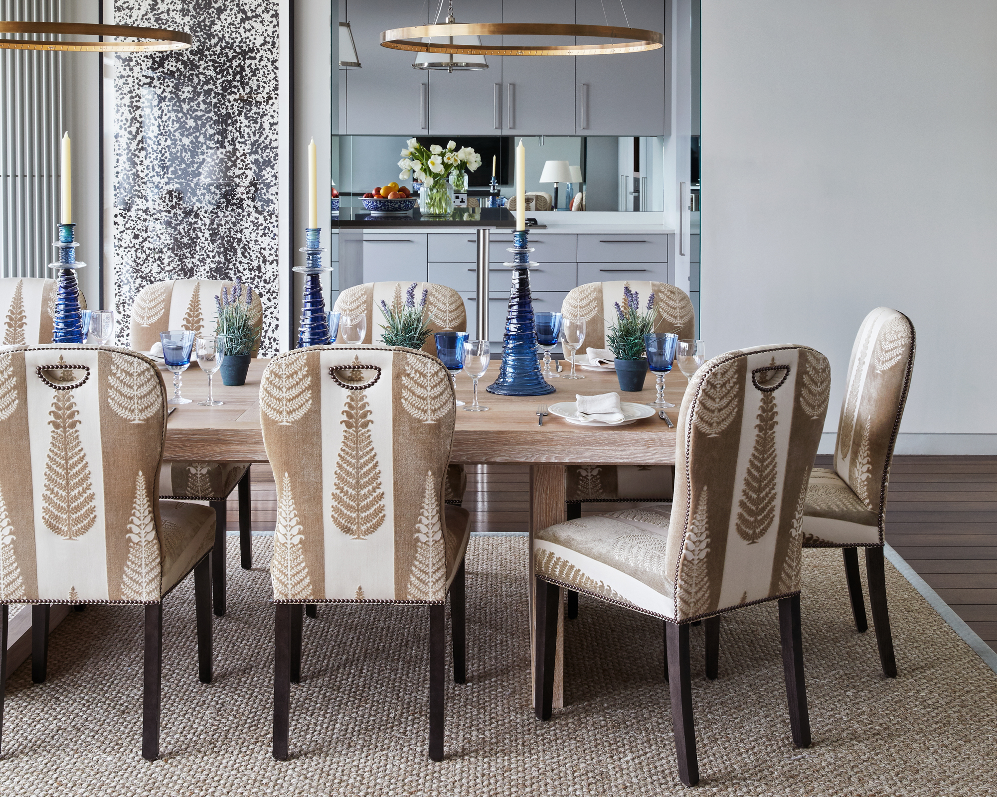 A dining table decor idea with neutral scheme, hanging ring pendant lights in brass and blue glass candlesticks and glasses