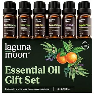 Essential Oils Set with 6 small amber glass bottles with black plastic twist top lids, lined up on its packacking box which is black and reads laguna moon essential oil gift seft with a graphic of a paire of orranges, with lavendar, and green herbal leaves. The bottles are labeled Peppermint, Tea Tree, Lavender, Eucalyptus, Lemongrass, Orange and are 10ml