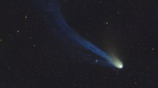 a bright dot leaves a hazy trail behind it as it flies in front of background stars