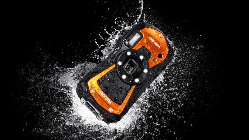 Ricoh WG-80 waterproof camera splashing in water with a plain black background