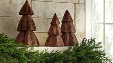 Rattan christmas trees lined up on a mantel with garland