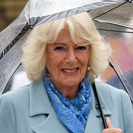 Queen Camilla wearing a blue coat holding an umbrella