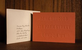 thick invitation embossed with the company's identity in a sans-serif block font