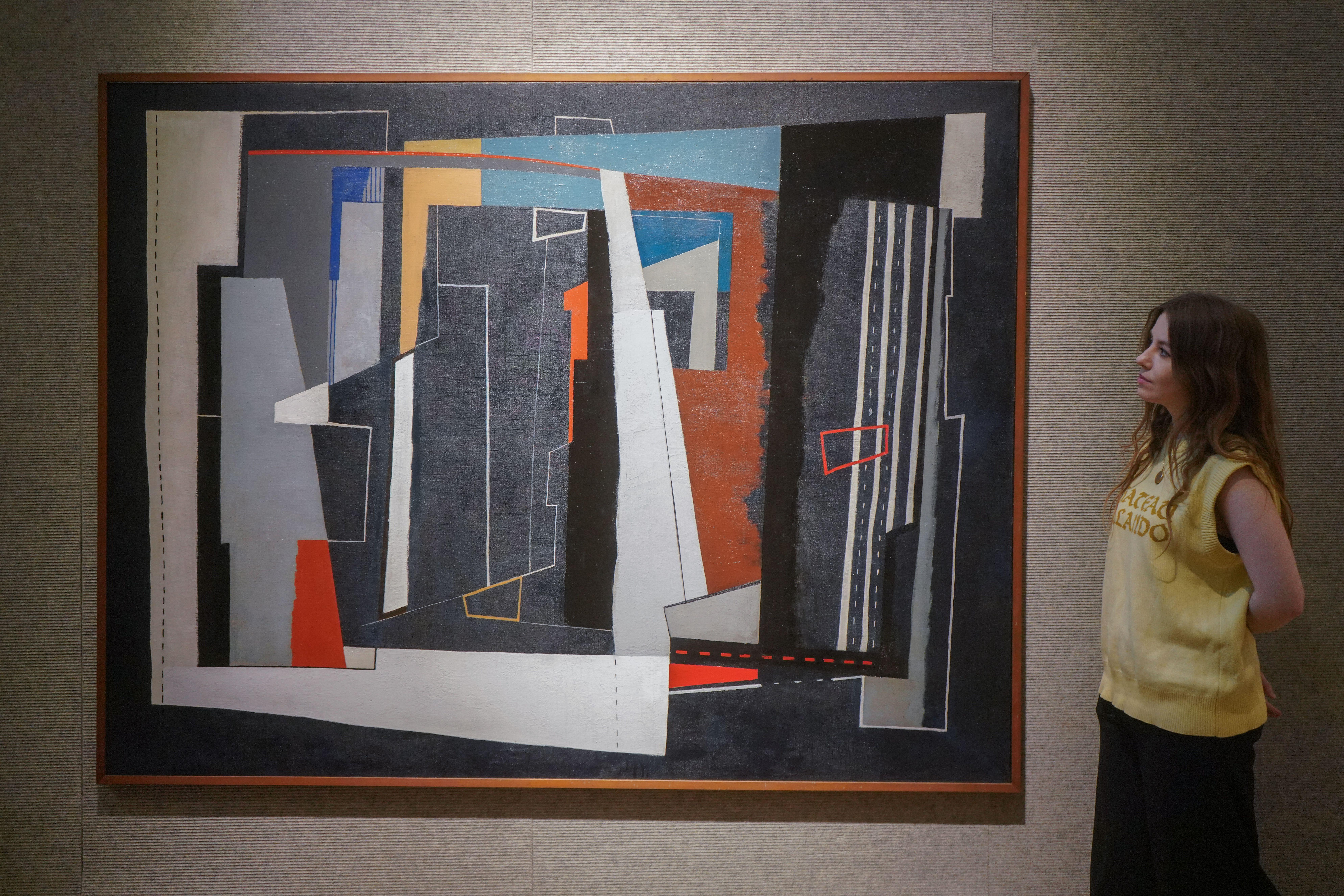 A woman looks at john Piper's modern creating Forms on Dark Blue ahead of a sale at Bonhams. It's an abstract work, quite similar to Miro and Picasso.