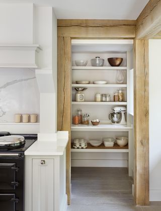 pantry with unpainted wooden frame and open shelving in white kitchen