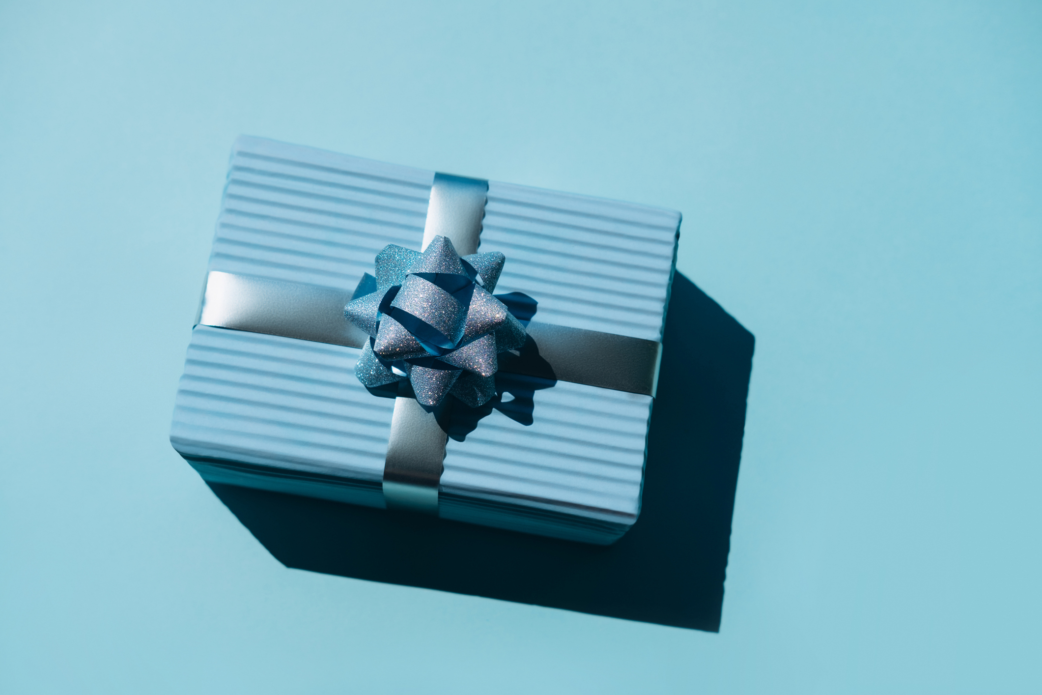 image of a gift box wrapped in blue stripped paper against a blue background