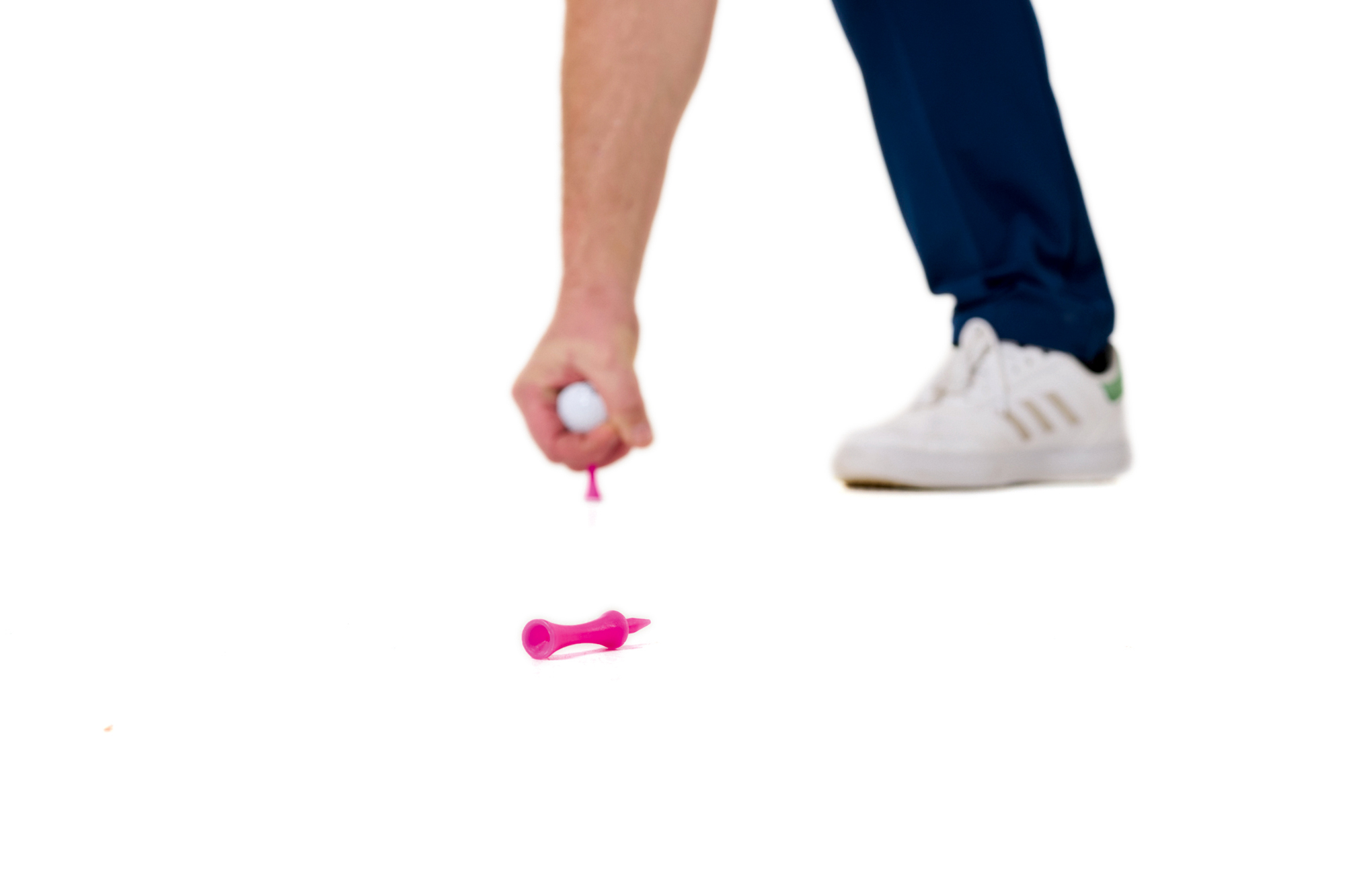 Russell Covey placing a pink castle tee in the ground, with a ball on top, around a club length behind a toppled over pink castle tee that will act as a secondary target for alignment purposes
