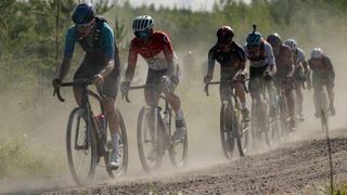 Gravel riders ride as a group through the dust